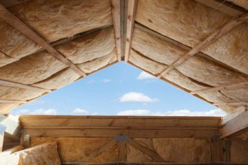 Exposed timber roof frame construction with insulation bats and blue sky visible