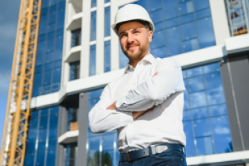 Construction site manager in a hard hat infront of a building