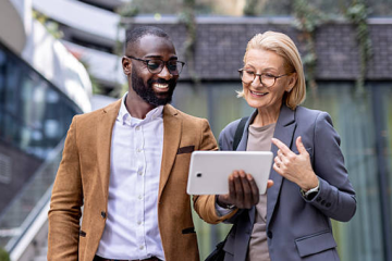 Two business professionals reviewing tablet outdoors discussing Arcsite property management Software